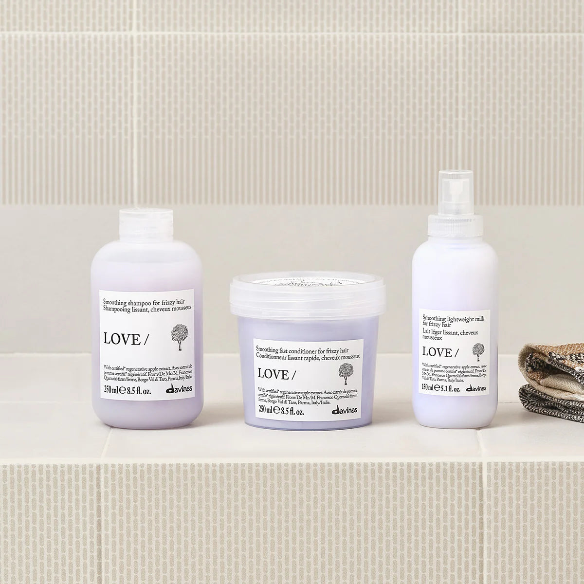 Three Davines hair care products on a bathroom shelf with a tiled wall background