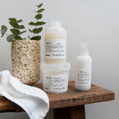 Set of haircare products on a wooden bench with a plant and hanging towel