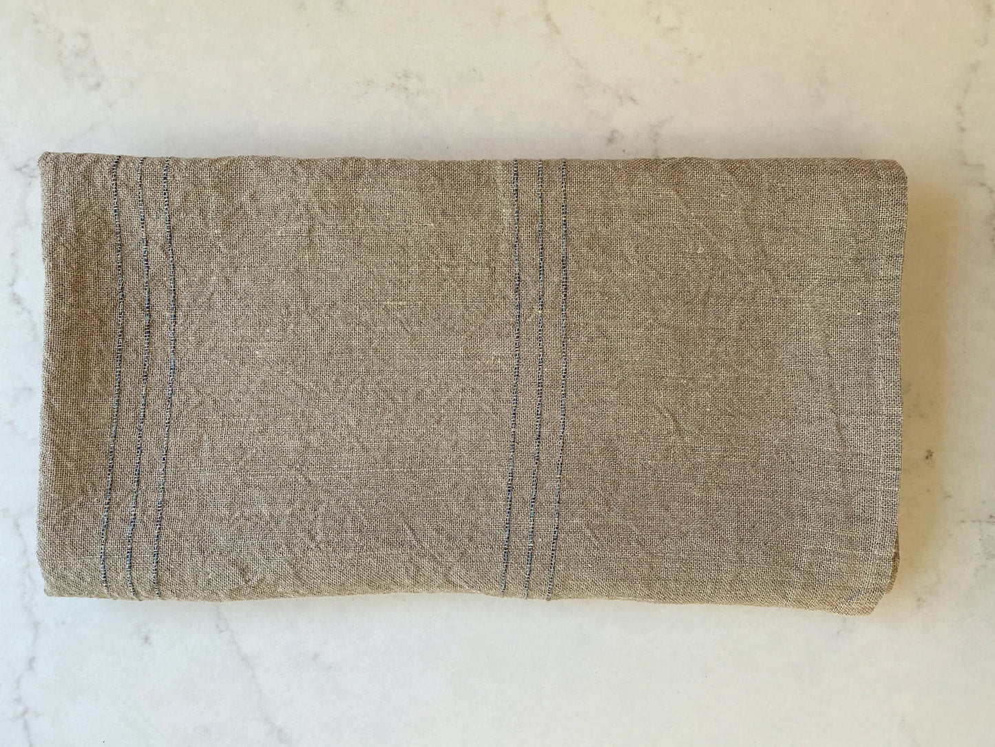 Beige towel with blue stitching on a marble surface