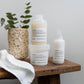 Set of Davines hair care products on a wooden bench with a plant and hanging towel.