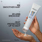 Redken hair care product being held with text highlighting benefits on a gray background