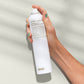 Hand holding a white spray bottle labeled 'evo' against a light background