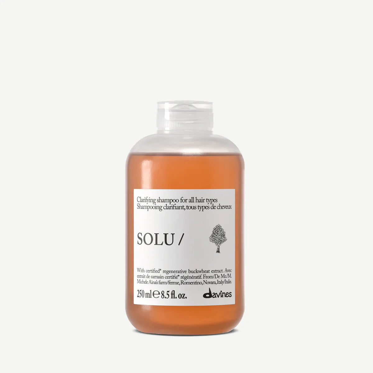 Bottle of Davines Solu Shampoo with white label against grey background