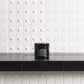 Black jar of hair butter on a black countertop with a white tiled wall background
