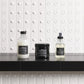 Three Davines hair care products on a black surface with a white tiled wall background