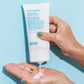 Right hand squeezing Head Mistress Cuticle Sealer into left hand against blue background