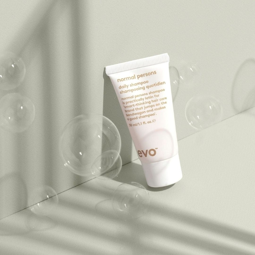 Tube of 'normal persons' shampoo on a light background with bubbles