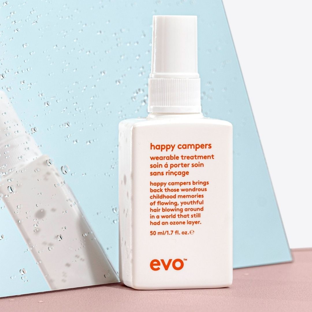 Evo happy campers hair treatment bottle on a light blue and pink background