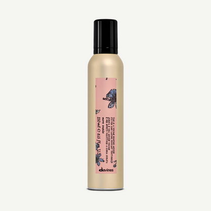 Bottle of Davines Volume Boosting Mousse with a pink label on a white background
