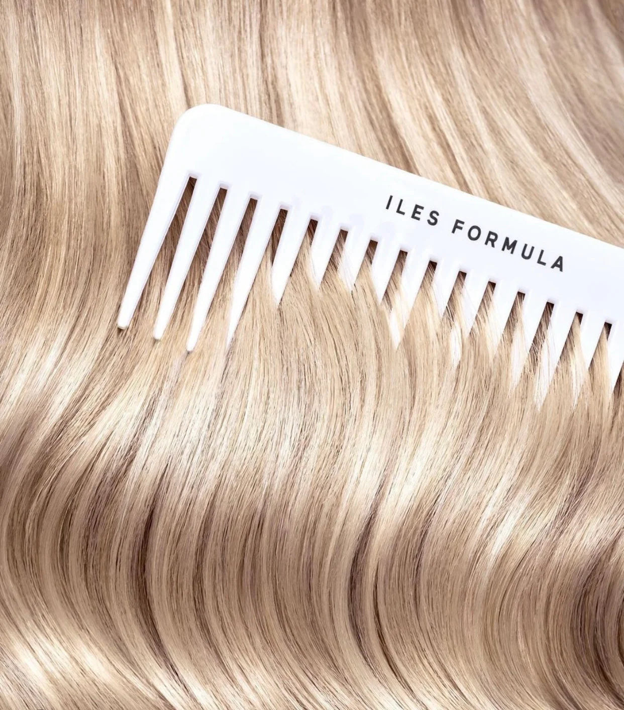 White comb with 'ILES FORMULA' branding on blonde hair