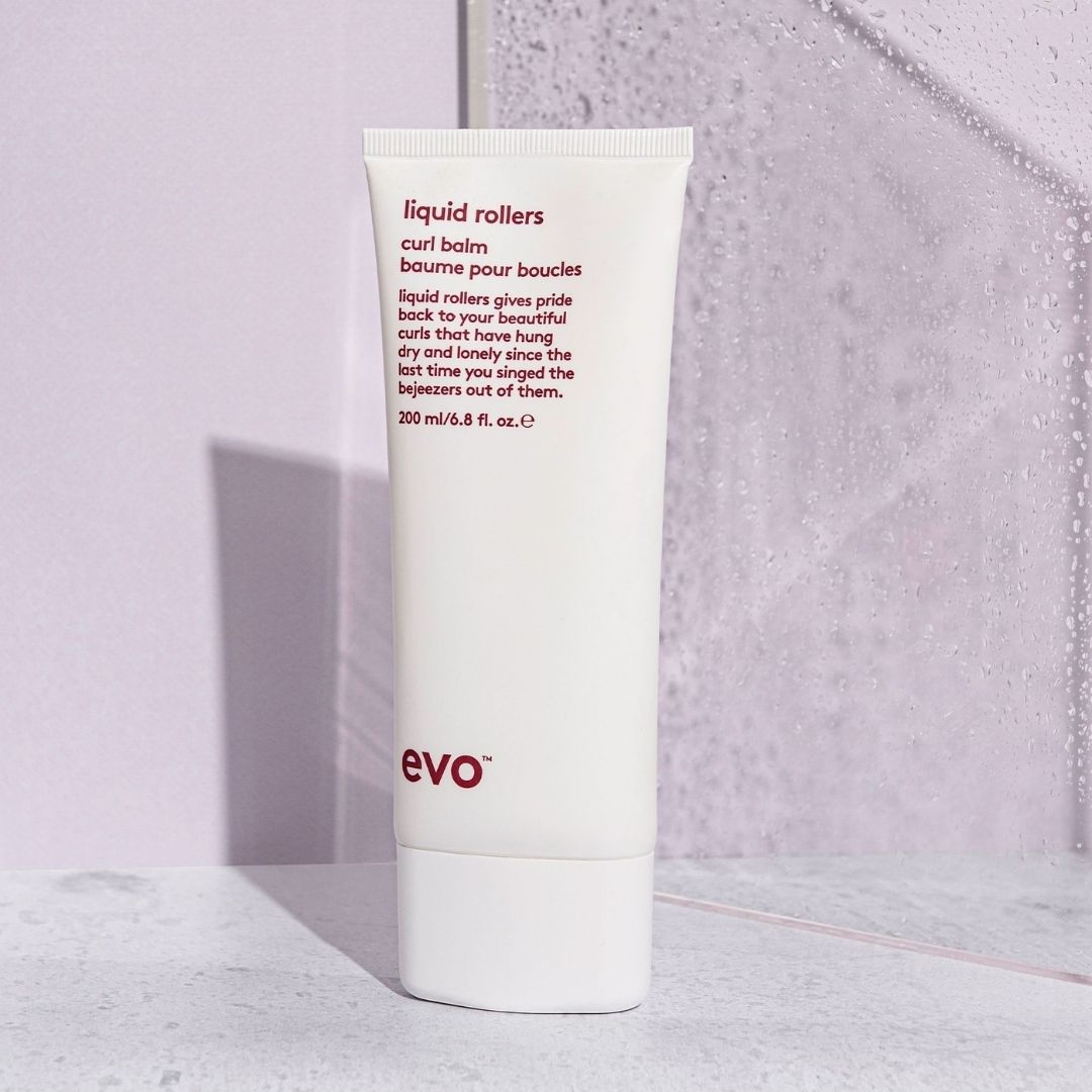 Tube of evo liquid rollers hair product on a textured surface with a light purple background