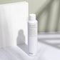 White bottle of evo hair product on a light surface with a neutral background