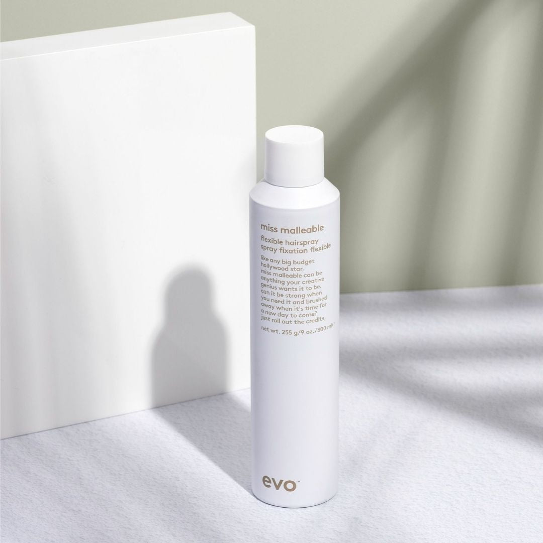 White bottle of evo hair product on a light surface with a neutral background