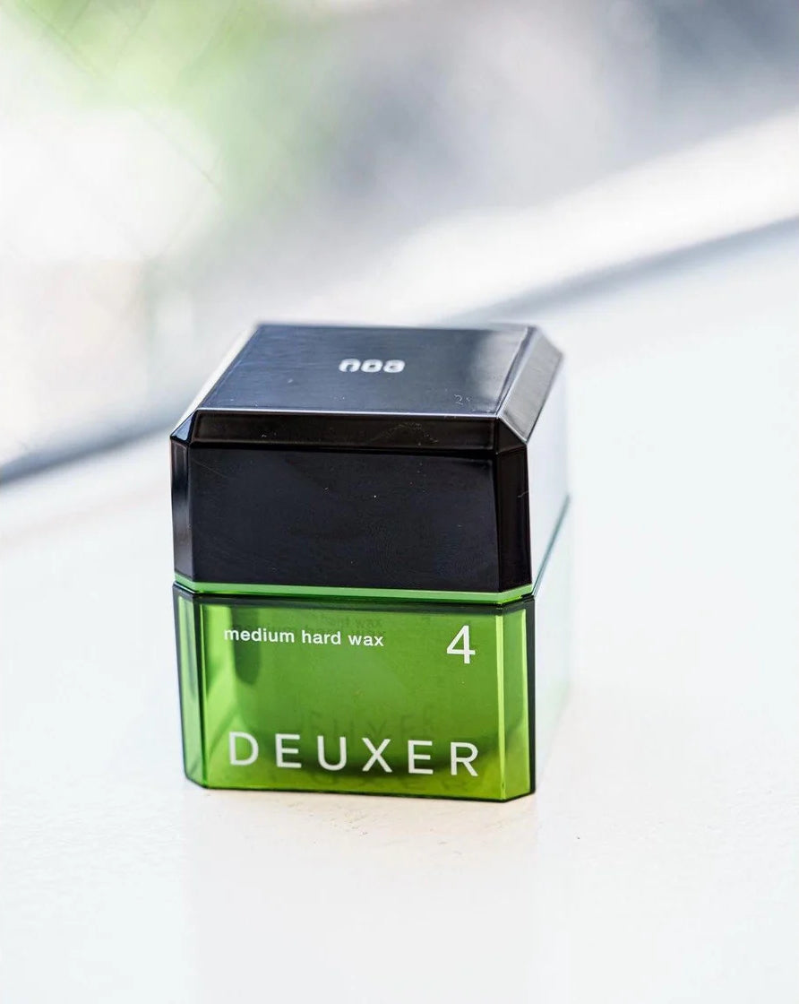 Green container of DEUXER medium hard wax on a white background