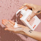 Person applying evo ritual salvation cream to their hand against a pink background