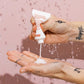Hand applying a white cream from a tube labeled 'EVO' against a pink background
