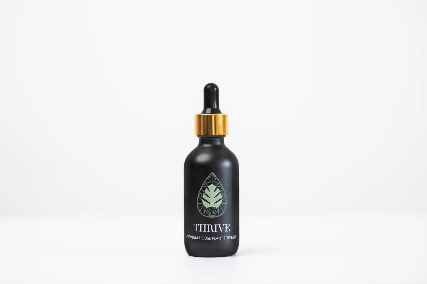 Black bottle with gold cap labeled 'Thrive' on a white background
