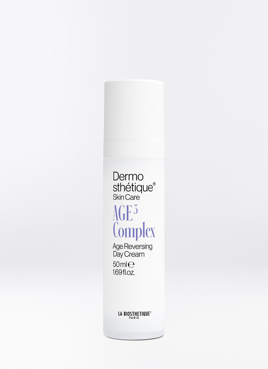 A white cylindrical bottle of Dermosthétique AGE3 Complex Age Reversing Day Cream, 50ml, on a light grey background.