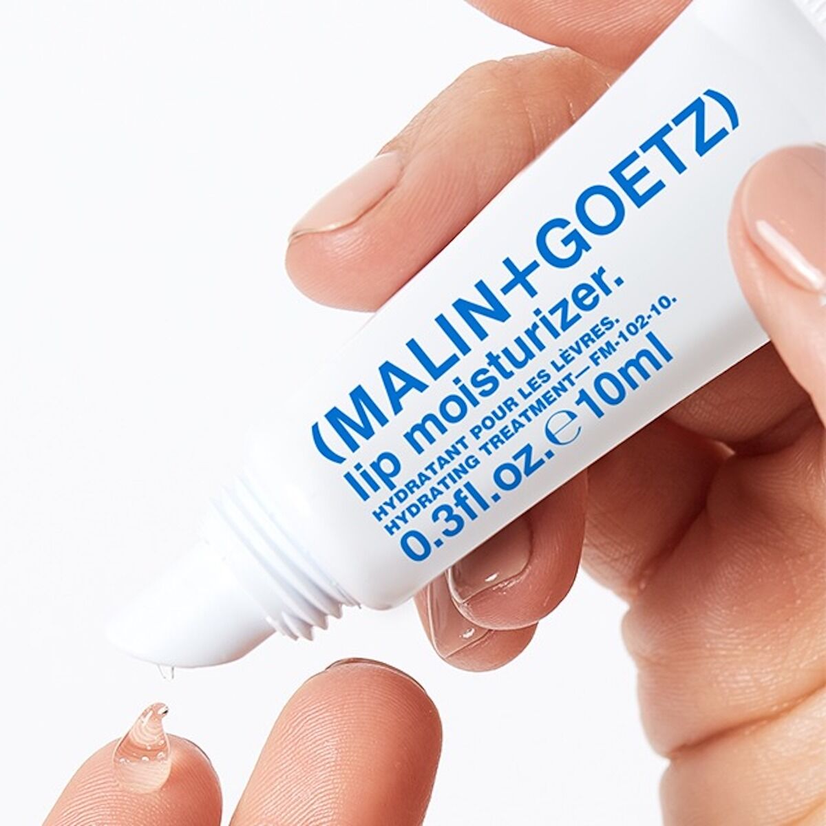 Hand holding a MALIN+GOETZ lip moisturizer tube with a white background