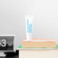 Malin+Goetz lip balm tube on books with a minimal background