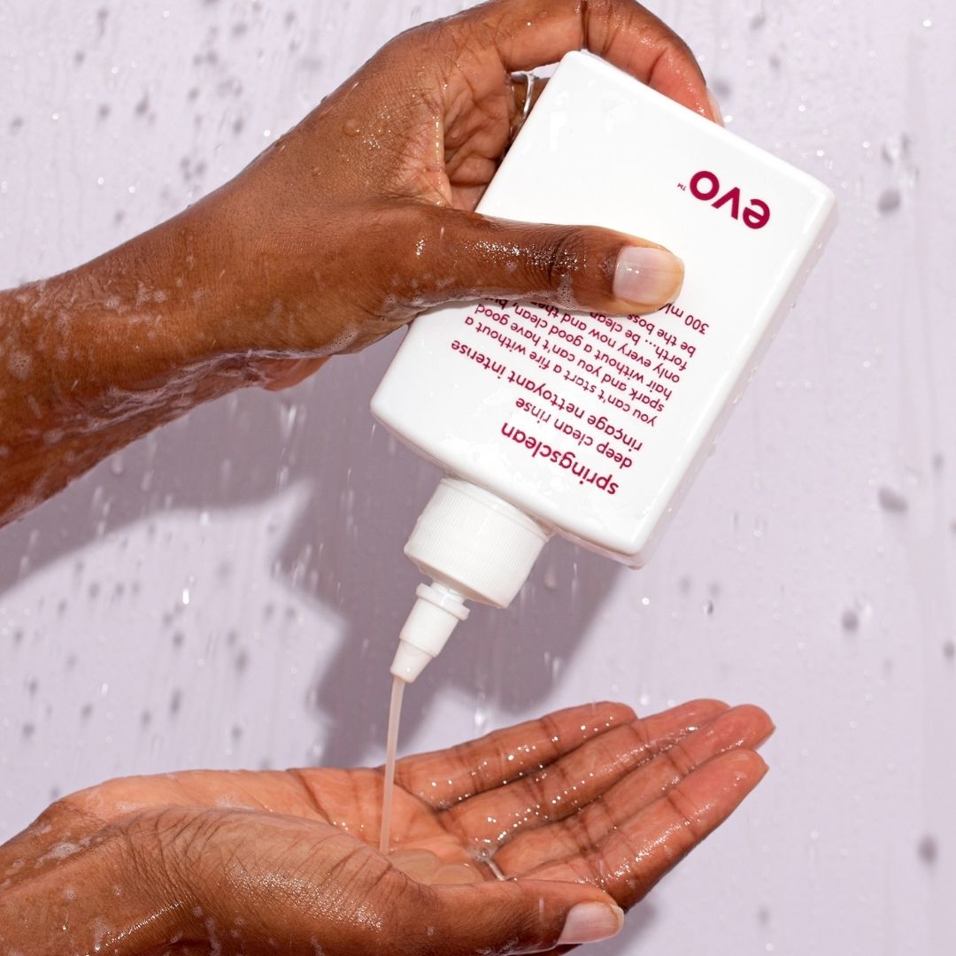 Person pouring Evo hair product into their hand with a shower in the background