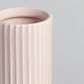 Pink ceramic vase with ribbed texture on a light gray background