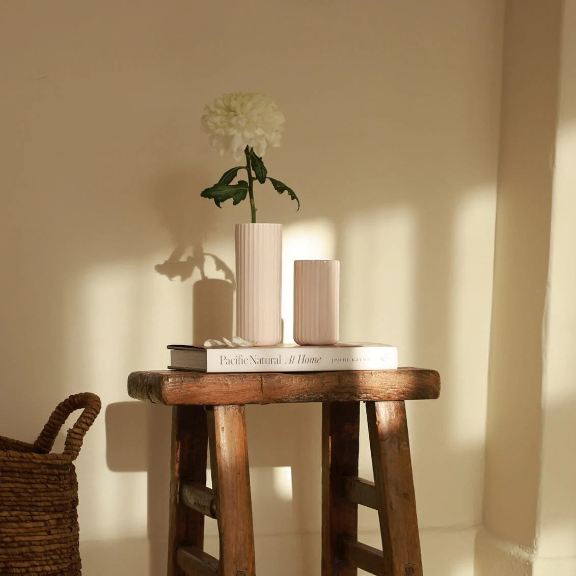 Wooden stool with books and a vase on a neutral background