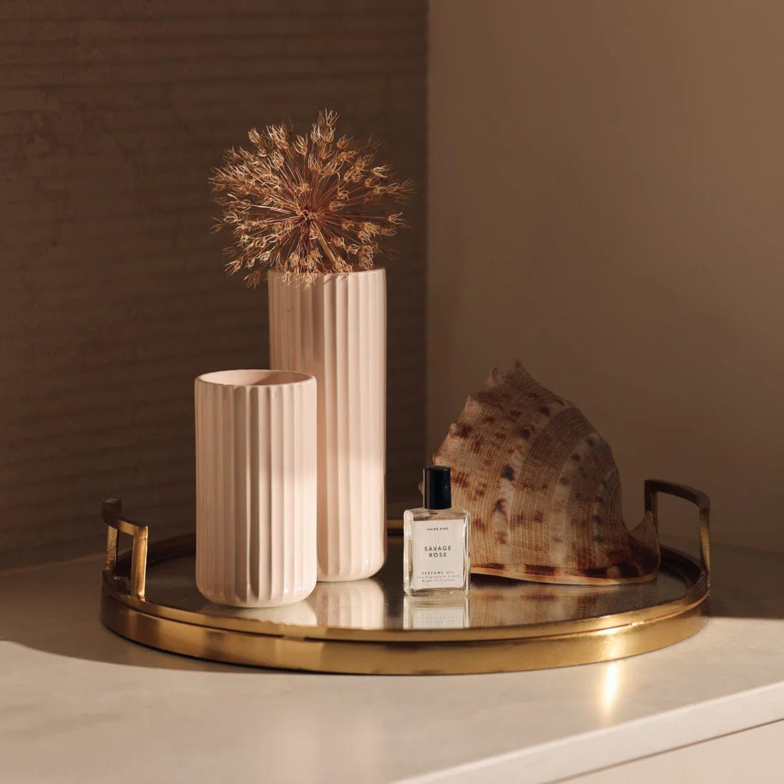 Decorative tray with vases, a shell, and a bottle on a neutral background