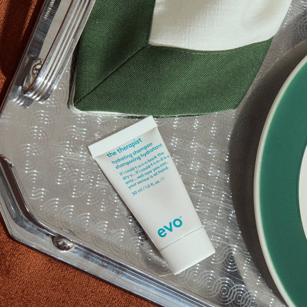 Tube of 'evo' product on a silver tray with a green and white plate and napkin